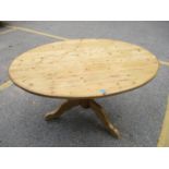 A rustic pine pedestal kitchen table, oval top supported on baluster column and splayed legs