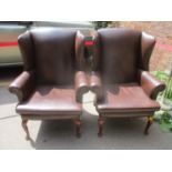 A pair of modern leather upholstered wing back armchairs, on mahogany finished cabriole legs by J