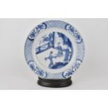 A Chinese Kangxi blue and white plate decorated with ladies at leisure, within a border of floral
