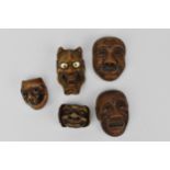 A collection of five Japanese carved wood mennetsuke (netsuke masks), comprising a Hannya mask,