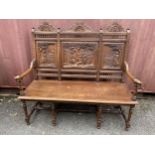 An early 20th century French carved oak bench with a carved, pierced panelled back with country