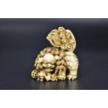 A Japanese Meiji period intricately carved ivory okimono of a Foo dog and young, with ball, modelled