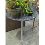 A kitchen bistro pedestal table with a stainless steel base and a granite top. Location:RAM