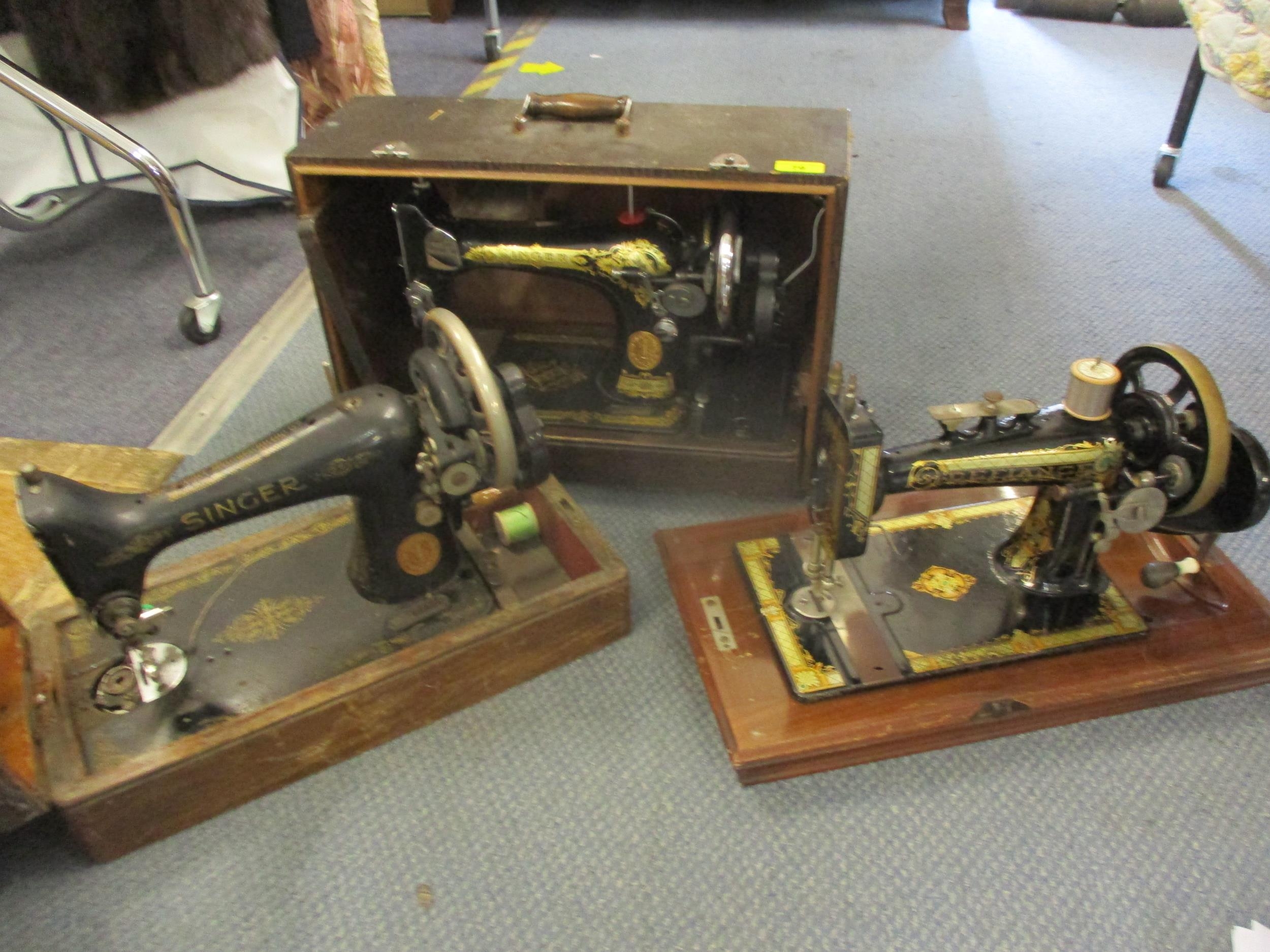 Three vintage Singer and Defiance sewing machines comprising model and serials Singer ED002125 dated