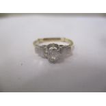 An 18ct yellow gold single stone ring with a platinum head and shoulders, claw set with a