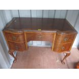 An early 20th century walnut veneered writing desk having a leather top scriber and five inset