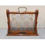 An early 20th century oak three bottle tantalus with original decanters and key Location: RWM