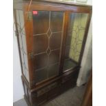 A late 20th century oak display cabinet with lead glazed panelled doors, over a pair of carved