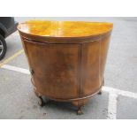 An early 20th century walnut quarter cut veneered bow fronted side cabinet standing on ball and claw