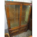 A late 20th century oak display cabinet with lead glazed, panelled doors over a pair of carved