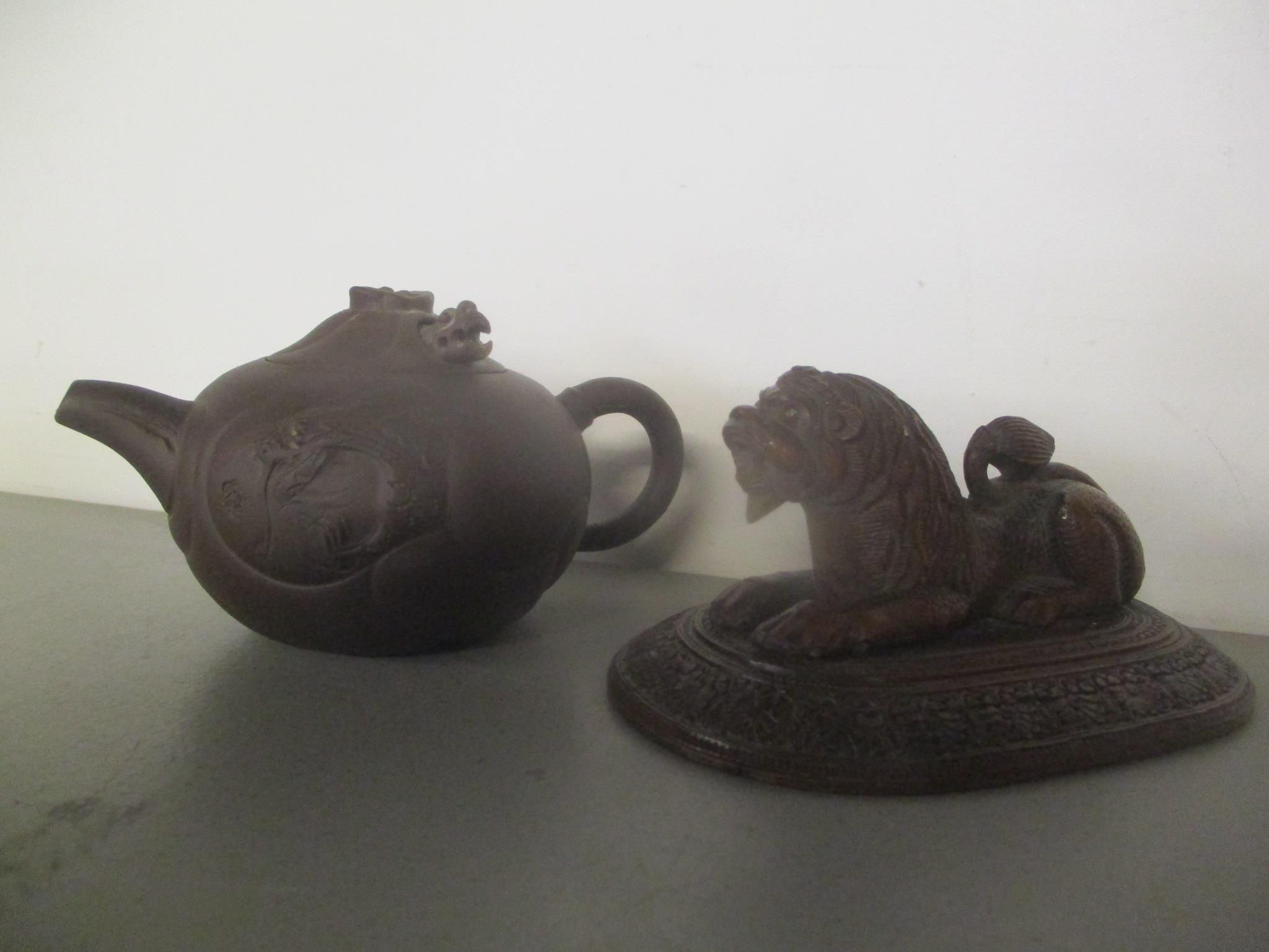 A 20th century Chinese Yixing Zisha pottery teapot and an Indian carved wooden model lion on a