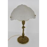 An early 20th century brass table lamp with a frosted floral glass shade, the stand having a