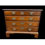 A George III mahogany chest of four long drawers having brass drop handles and shaped bracket