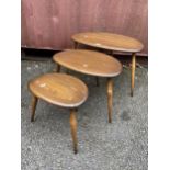 A nest of three mid 20th century Ercol dark stained elm and beechwood 'Pebble' occasional tables,