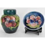 A Moorcroft Hibiscus ginger jar by Walter Moorcroft on a green ground 15cm high together with a