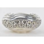 A white metal continental bowl having inverted rim, wavy and floral embossed decoration, the base