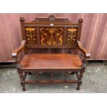 An Art Nouveau mahogany two seater bench having marquetry floral inlaid panels, scrolled shaped arms