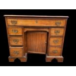 A George III mahogany kneehole desk of one long and six short drawers with brass drop handles