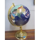 A blue gemstone globe with gold coloured mount and stand, where each country is represented by a