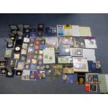 A collection of various commemorative coins and medals and banknotes, many in original packaging and