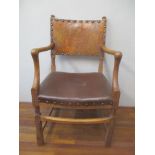 A Heals style lined oak framed open arm chair, with a leather back and seat, on carved legs