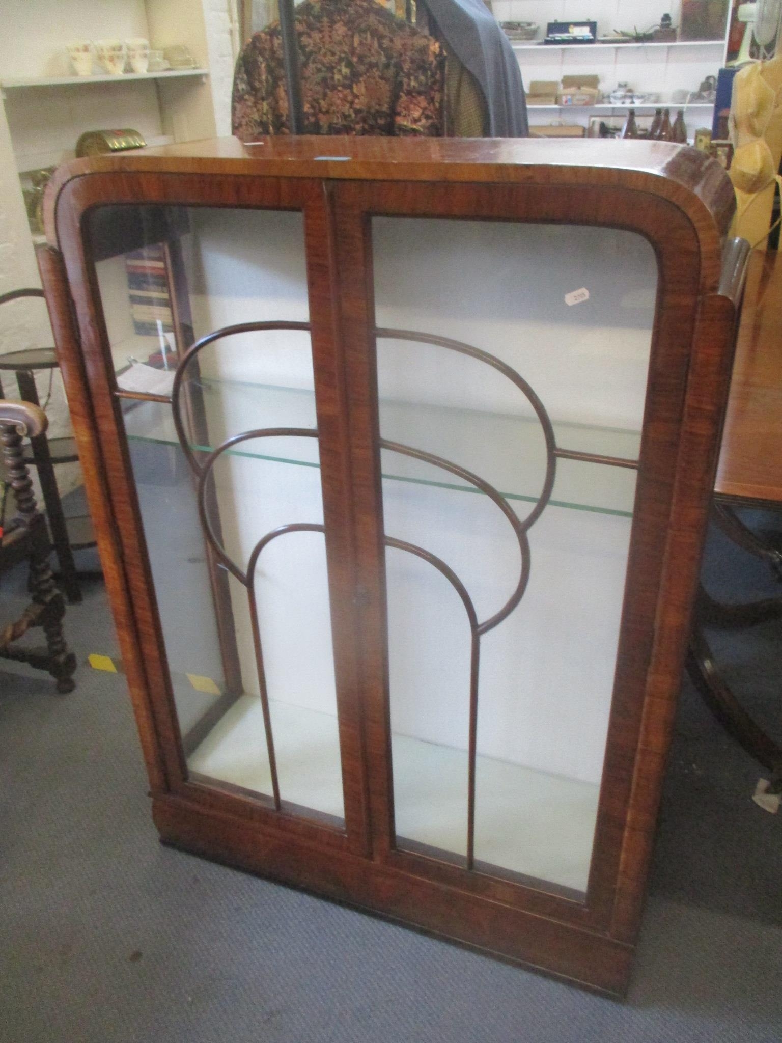 An Art Deco walnut veneered display cabinet having twin glazed doors and two loose glass shelves,