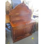 A Victorian mahogany chiffoniere having a carved, raised top, serpentine front and drawer above twin