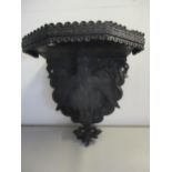 A Black Forest style wooden wall bracket, the support below in the form of a carved mystical bird