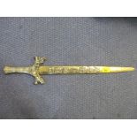 A Chinese brass copy of a Chinese dagger decorated with raised cast calligraphy to the blade, iron