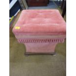 A square formed bedroom stool in a pink velour upholstery with tassel fringe having a mahogany