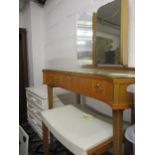 A vintage teak small dressing table having a tri-fold mirror above three drawers and on beach