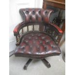 A reproduction leather button back captain's style swivel armchair