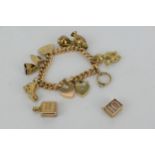 A 15ct gold curb link bracelet with a padlock style clasp, ten 9ct gold charms, 42g and a gold