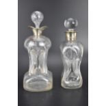 Two late 19th/early 20th century clear glass glug glug decanters, each with a silver collar, one