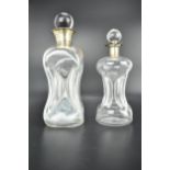 Two clear glass glug glug decanters, one with a flared silver collar, marks rubbed h and a late