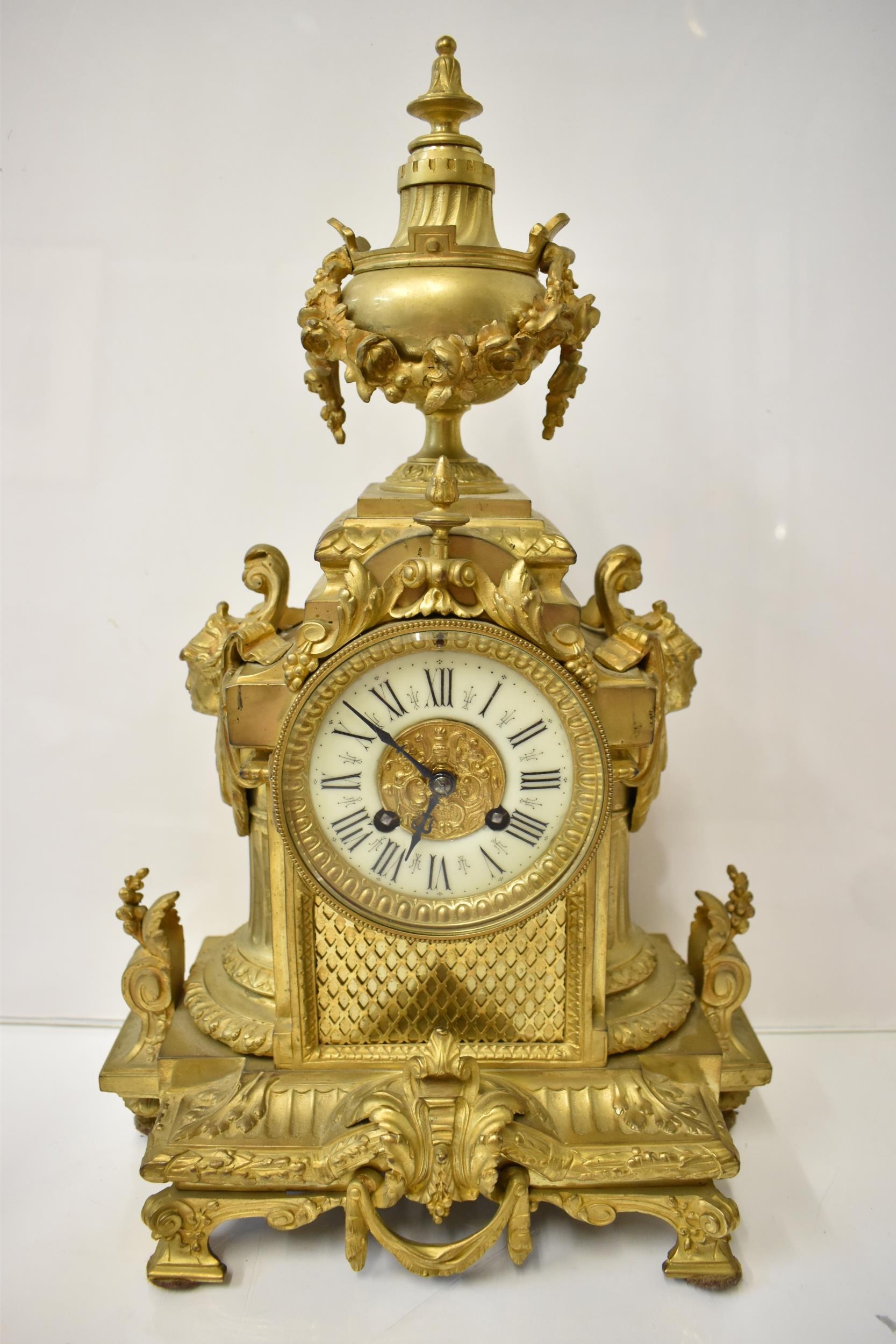 A 19th century French gilt metal mantel clock, the case having an urn shaped finial with floral