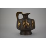 A 20th century heavy cast bronze jug with a polished handle and patinated body, decorated with