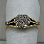 An 18ct gold and platinum daisy ring set with seven diamonds to the centre franked by diamond set