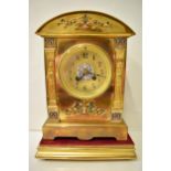 An early 20th century brass mantle clock on a gilded treen stand, the arched top case with floral