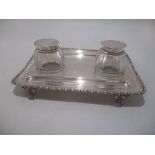 An early 20th century silver desk stand with a pair of removable glass inkwell and pen channels, the