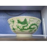 A Chinese porcelain bowl decorated with two green glaze dragons chasing flaming pearls on an incised