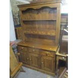 A reproduction pine dresser having plate rack with four inset drawers above three drawers and