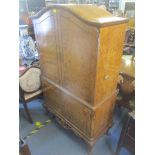 A 1950's walnut cocktail cabinet having four cupboard doors with fitted interior standing on short