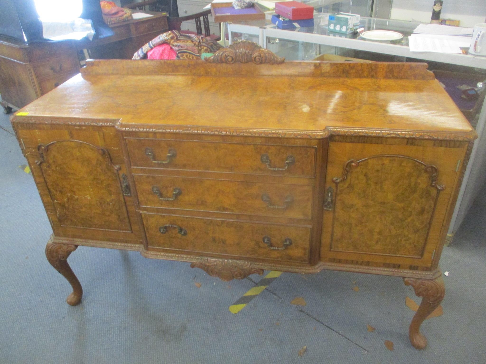 A 1950's walnut breakfront sideboard having three drawers flanked by two cupboard doors standing