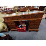 A reproduction yew twin pedestal desk having a green leather topped scriber with nine drawers,