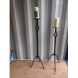 A pair of wrought iron floor standing candle sticks, 90cm high and 106cm high and a pair of church