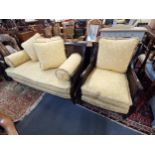 An early 20th century mahogany bergere sofa and matching armchair with double caned sides and carved