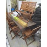 A garden teak table, 74.5cm h x 150cm w, together with four folding chairs and a boxed parasol