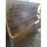 A modern large pine dresser having a plate rack with two shelves above four drawers and four