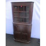 An early 20th century oak corner cabinet having single glazed door above a panelled door and on a